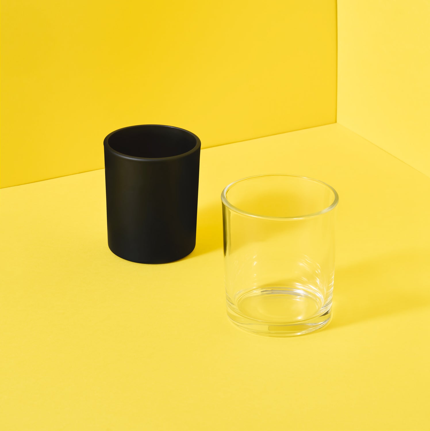 Black and clear candle glass jars on yellow background