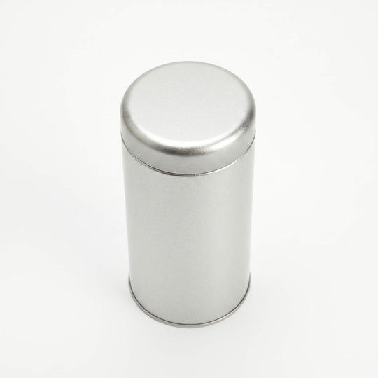 Round silver metal tea tin with fitted slip lid viewed from top angle on white background.
